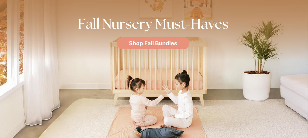  Two children playing in a nursery with a crib and fall leaves through window.